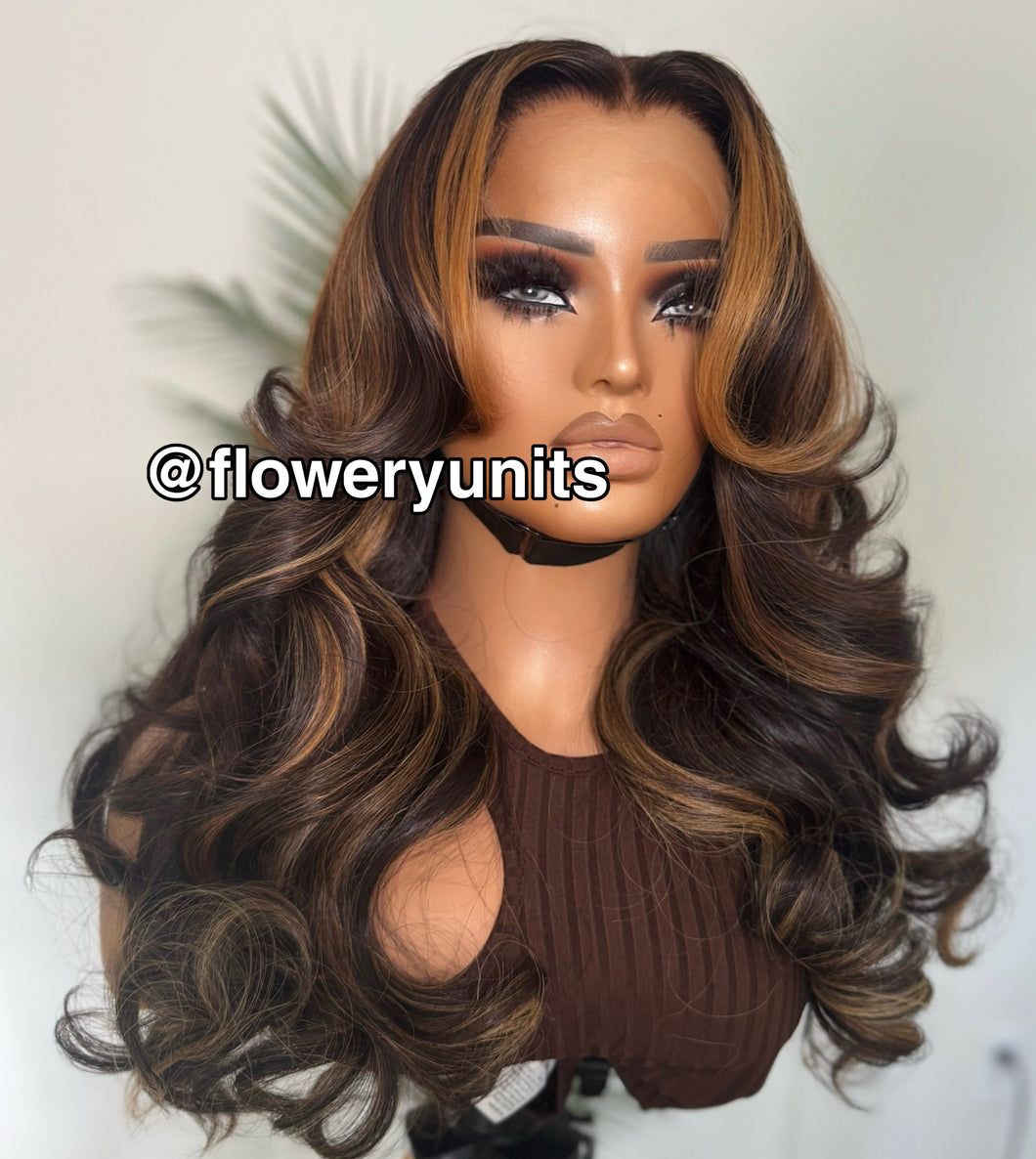 Image of a mannequin head with a glueless closure brown wig featuring honey blonde highlights. The wig is lightly layered and styled in cascading curls. The wig has curtain bangs and face framing layers.